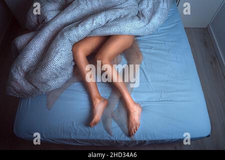 Femme dormant dans le lit et souffrant du syndrome de RLS ou des jambes sans repos Banque D'Images