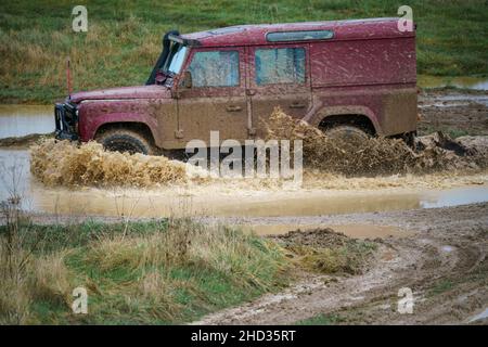 Un véhicule Land Rover 110 LWB conduit hors route à travers les eaux profondes et boueuses de Salisbury Plain Royaume-Uni Banque D'Images