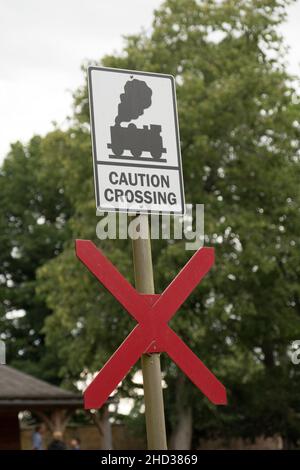 Vue verticale d'un panneau « attention Crossing » au-dessus d'une grande croix rouge sur la route Banque D'Images