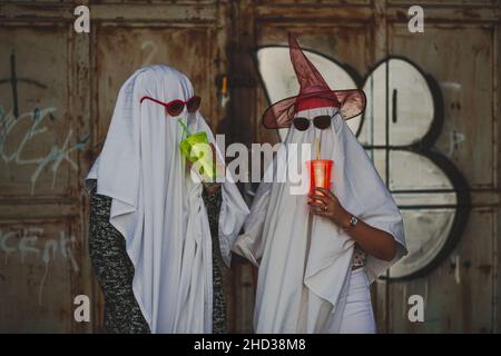 Image drôle de deux personnes en costumes de fantôme boire d'un cu Banque D'Images