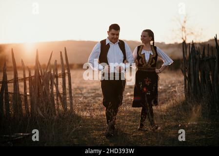 Jeune couple multiracial dansant dans un costume traditionnel serbe dans un champ en Serbie Banque D'Images
