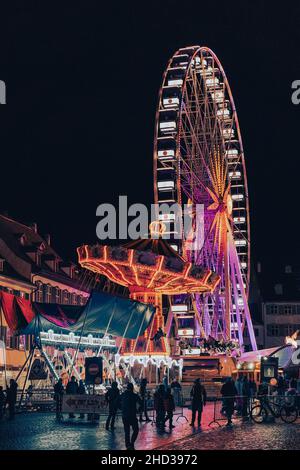 Plan vertical de la grande roue de Basler HERBSTMESSE entouré de lumières la nuit en Suisse Banque D'Images