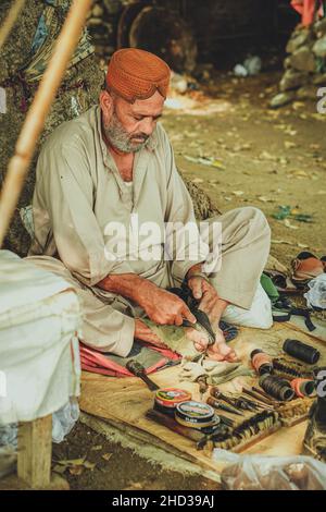 Pauvre homme de chaussure cobbler assis sous un arbre dans un magasin local de rue du Pakistan avec ses outils Banque D'Images