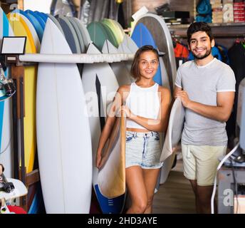 Couple d'homme positif avec des planches de surf dans la boutique Banque D'Images