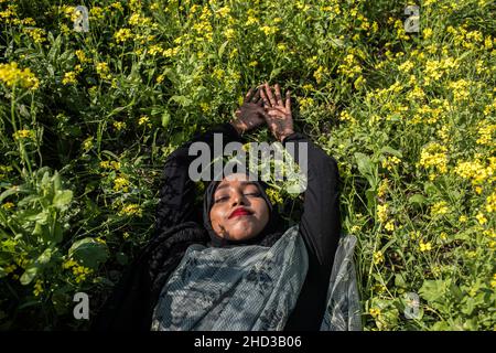 Dhaka, Bangladesh.31st décembre 2021.Une femme pose pour une photo dans un champ de moutarde jaune à la périphérie de Dhaka.La moutarde est une culture de temps frais et est cultivée à partir de graines semées au début du printemps, de la mi-décembre à la fin janvier, les agriculteurs bangladais cultivent leurs récoltes de fleurs de moutarde jaune aux couleurs vives qui sont en pleine floraison.Crédit : SOPA Images Limited/Alamy Live News Banque D'Images