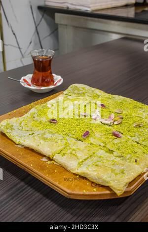 Délicieux dessert turc à la pistache Katmer avec un verre de thé en gros plan. Banque D'Images