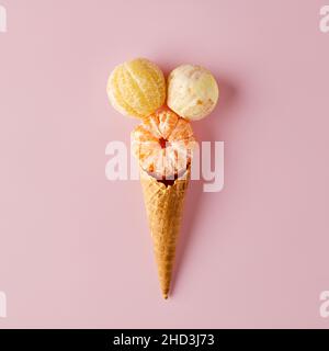 Cône de crème glacée avec agrumes pelés sur fond rose pastel.Concept alimentaire biologique d'été minimal. Banque D'Images