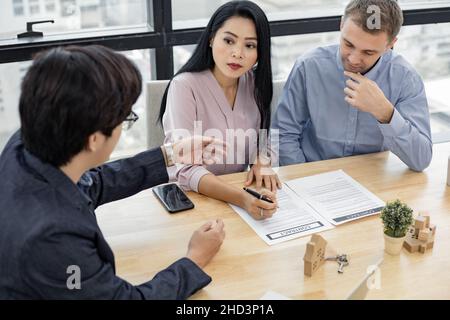 Le couple a signé le contrat d'achat de maison avec les agents de vente de maison.Acheter ou vendre le concept de maison.Couple heureux dans transaction signature contrat de la maison Banque D'Images