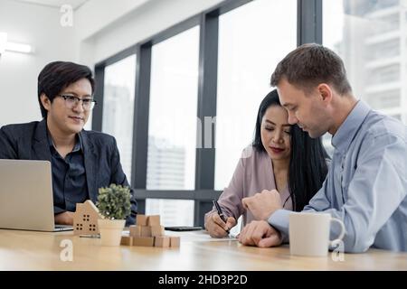 Le couple a signé le contrat d'achat de maison avec les agents de vente de maison.Acheter ou vendre le concept de maison.Couple heureux dans transaction signature contrat de la maison Banque D'Images