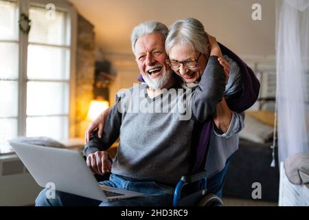 Couple senior heureux utilisant un ordinateur portable à la maison et s'amusant ensemble. Concept de personnel technologique Banque D'Images