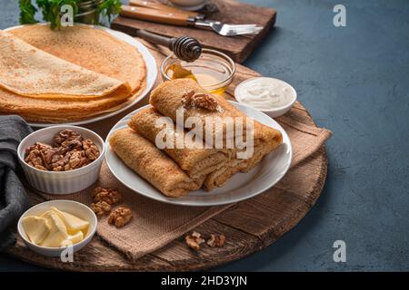 Crêpes fourrées maison avec fromage cottage sur fond de noix, de miel et de crème aigre. Banque D'Images
