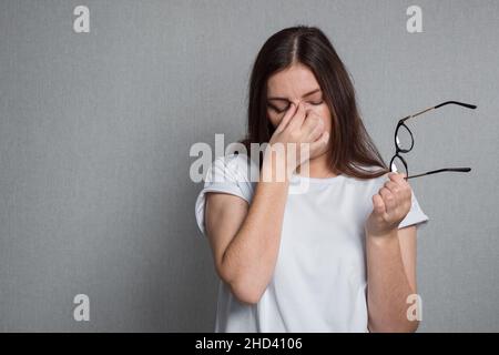 La femme fatiguée prend des lunettes de vue et frotte les yeux Banque D'Images