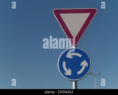 Gros plan d'un panneau de signalisation de rendement et de rond-point fixé sur un poteau métallique Banque D'Images