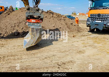 Une pelle tire un camion benne avec un cordon pour l'aider à sortir du sable sur le chantier. Banque D'Images