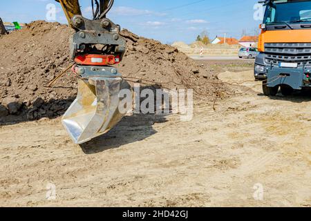 Une pelle tire un camion benne avec un cordon pour l'aider à sortir du sable sur le chantier. Banque D'Images