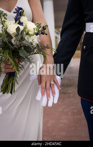 Plan vertical d'une mariée et d'un marié en tenant les mains uniformes Banque D'Images