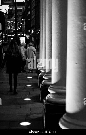 Photo verticale des personnes marchant sur un trottoir près d'un hôtel, Londres, Angleterre, image en niveaux de gris Banque D'Images