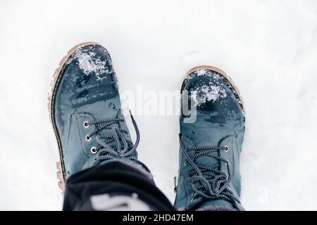 Gros plan des bottes chaudes bleu hiver avec lacets dans la neige pour créer des empreintes de pas sur le sol recouvert de neige.Arrière-plan étonnant plein de blanc et Banque D'Images