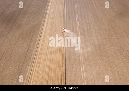 Photo d'un drone aérien d'un tracteur cultivant un champ après la récolte estivale. Banque D'Images