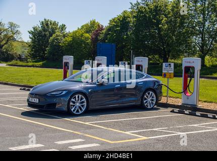 Grantham, Royaume-Uni - Mai 30th 2021 : le berline Tesla est branchée dans un compresseur de suralimentation dans une zone de service.Photo de haute qualité Banque D'Images