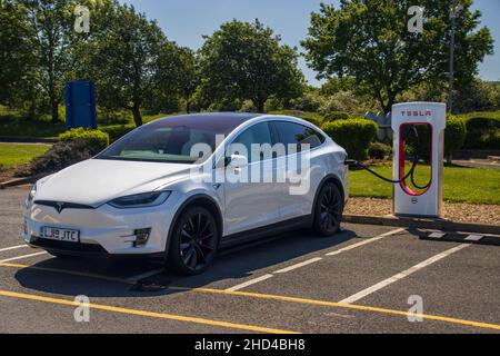 Grantham, Royaume-Uni - Mai 30th 2021: Un whiteTesla modèle x branché dans un compresseur à un service d'autoroute.Photo de haute qualité Banque D'Images