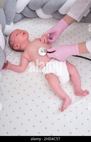 Femme médecin écoute avec un stéthoscope à un nouveau-né. L'infirmière vérifie la santé de l'enfant à l'aide d'un stéthoscope Banque D'Images