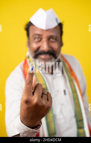 Mise au point sélective à portée de main, portrait d'un homme politique souriant heureux montrant l'encre marquée du doigt après avoir voté dans les sondages d'élection - présentation de concept