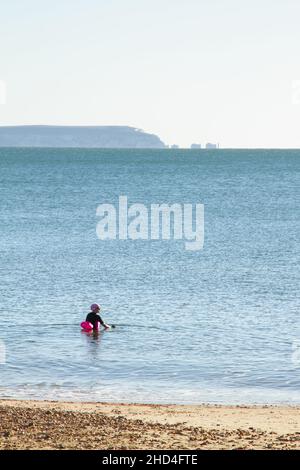 Nageur sauvage Femme naissant dans la mer en hiver au large d'Avon Beach avec Une vue sur le Solent vers l'île de Wight et les aiguilles Royaume-Uni Banque D'Images