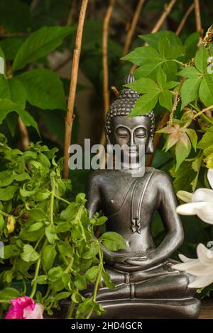 Statue décorative de Bouddha Gautama dans un jardin fleuri Banque D'Images