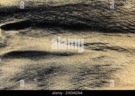 Motif abstrait fait par des vagues sur le sable noir volcanique de l'île de Bali Banque D'Images