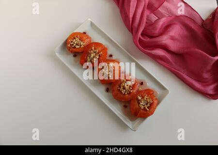 Dessert de coing, coing cuit au four dans du sirop épais.Plaque blanche et fond blanc.Concept et idée de présentation alimentaire.Cuisine turque traditionnelle. Banque D'Images