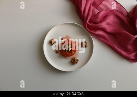 Dessert de coing, coing cuit au four dans du sirop épais.Plaque blanche et fond blanc.Concept et idée de présentation alimentaire.Cuisine turque traditionnelle. Banque D'Images