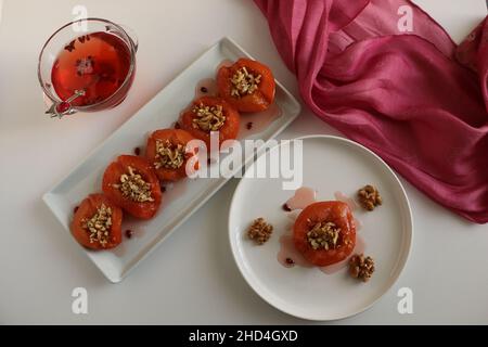 Dessert de coing, coing cuit au four dans du sirop épais.Plaque blanche et fond blanc.Concept et idée de présentation alimentaire.Cuisine turque traditionnelle. Banque D'Images