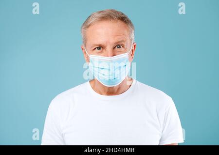 Homme mature portant un masque médical de protection au studio Banque D'Images