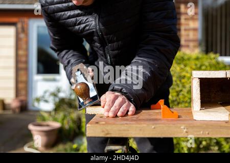 Gros plan d'un jeune homme utilisant un rabot à main sur un projet DIY, DIY, construction, concept d'amélioration de la maison Banque D'Images