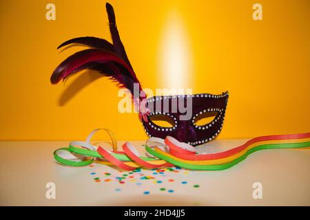 masque de carnaval violet avec confetti sur fond jaune et papiers de couleurs Banque D'Images