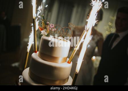 Gros plan de gâteau de mariage avec bougies allumées et fêtes de mariée et de marié Banque D'Images