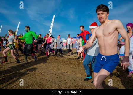 Les nageurs qui s'indécoupent dans la mer de l'estuaire de la Tamise à Southend on Sea, Essex, Royaume-Uni, pour une baignade caritative du nouvel an pour le RNLI Banque D'Images