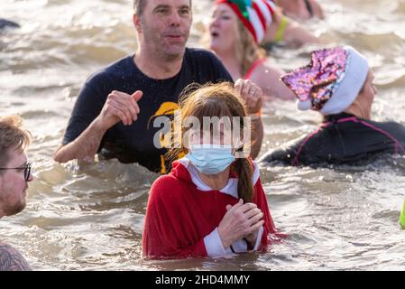 Nageurs dans la mer de l'estuaire de la Tamise à Southend on Sea, Essex, Royaume-Uni, pour un mouvement caritatif du jour de l'an nagez pour le RNLI.Femme dans le masque facial Banque D'Images