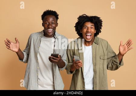 Offre mobile.Portrait de deux amis noirs excités avec un smartphone entre les mains Banque D'Images