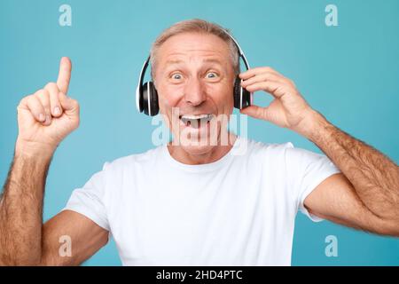 Portrait de tête d'un homme mature excité portant un casque sans fil Banque D'Images