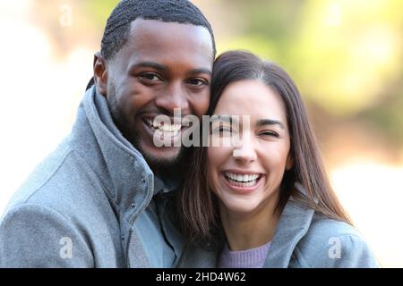 Heureux couple interracial riant avec des dents blanches à la caméra en hiver Banque D'Images