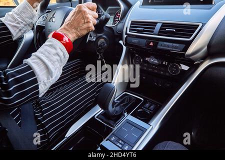 Femme d'âge élégante conduisant une voiture chère Banque D'Images