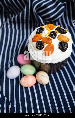 Les œufs de Pâques décorés d'aquarelles et de gâteau de Pâques sont placés sur un tablier bleu rayé. Concept de vacances religieuses de Pâques, vue de dessus Banque D'Images