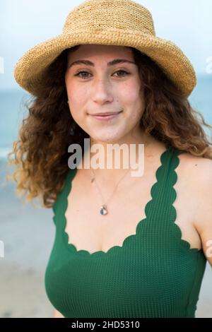 Portrait de la jeune femme à la plage en chapeau et maillot de bain vert Banque D'Images