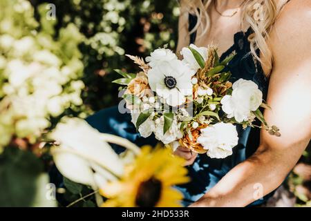 La femme blanche tient un bouquet de fleurs sauvages coupées fraîches sera assise Banque D'Images