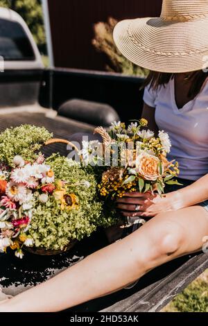 Une femme est assise sur un lit de camion pour préparer des fleurs de jardin fraîches Banque D'Images