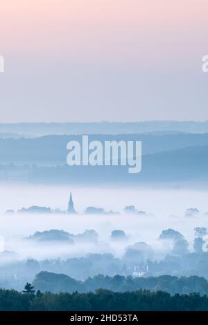 Le clocher de l'église Saint-Barnabas à Weeton s'élève au-dessus des brouillards qui s'élèvent au-dessus des pâturages d'Arthington sur un matin frais de début d'automne avant le lever du soleil. Banque D'Images