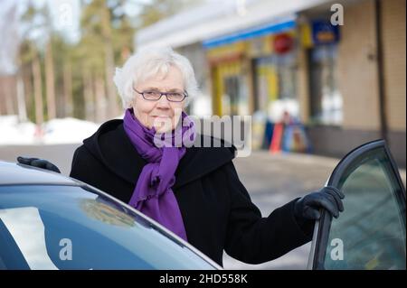 Femme âgée et élégante debout à côté de sa voiture. Banque D'Images