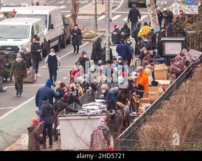 Des bénévoles distribuent des vêtements, des couvertures et d'autres achats pour temps froid aux sans-abri et aux pauvres devant l'église des Saints Apôtres à Chelsea, à New York, le 24 décembre 2021.(© Richard B. Levine) Banque D'Images